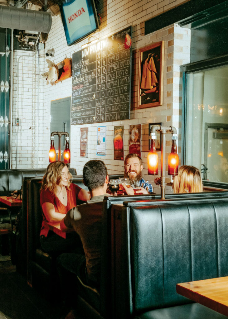 Group of adults sitting in booth toasting with beverages in hand