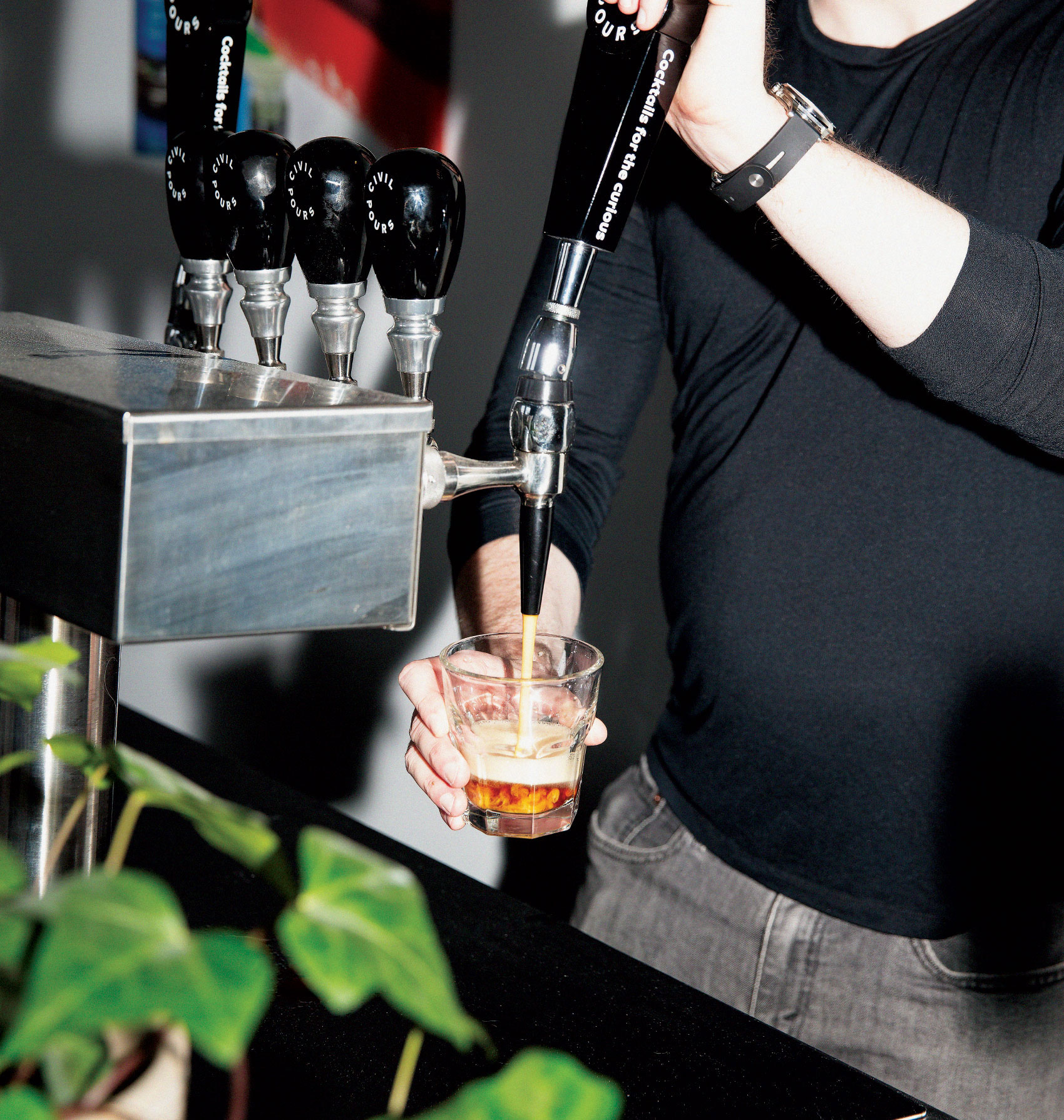 Man pouring Civil Pour cocktail in glass from tap