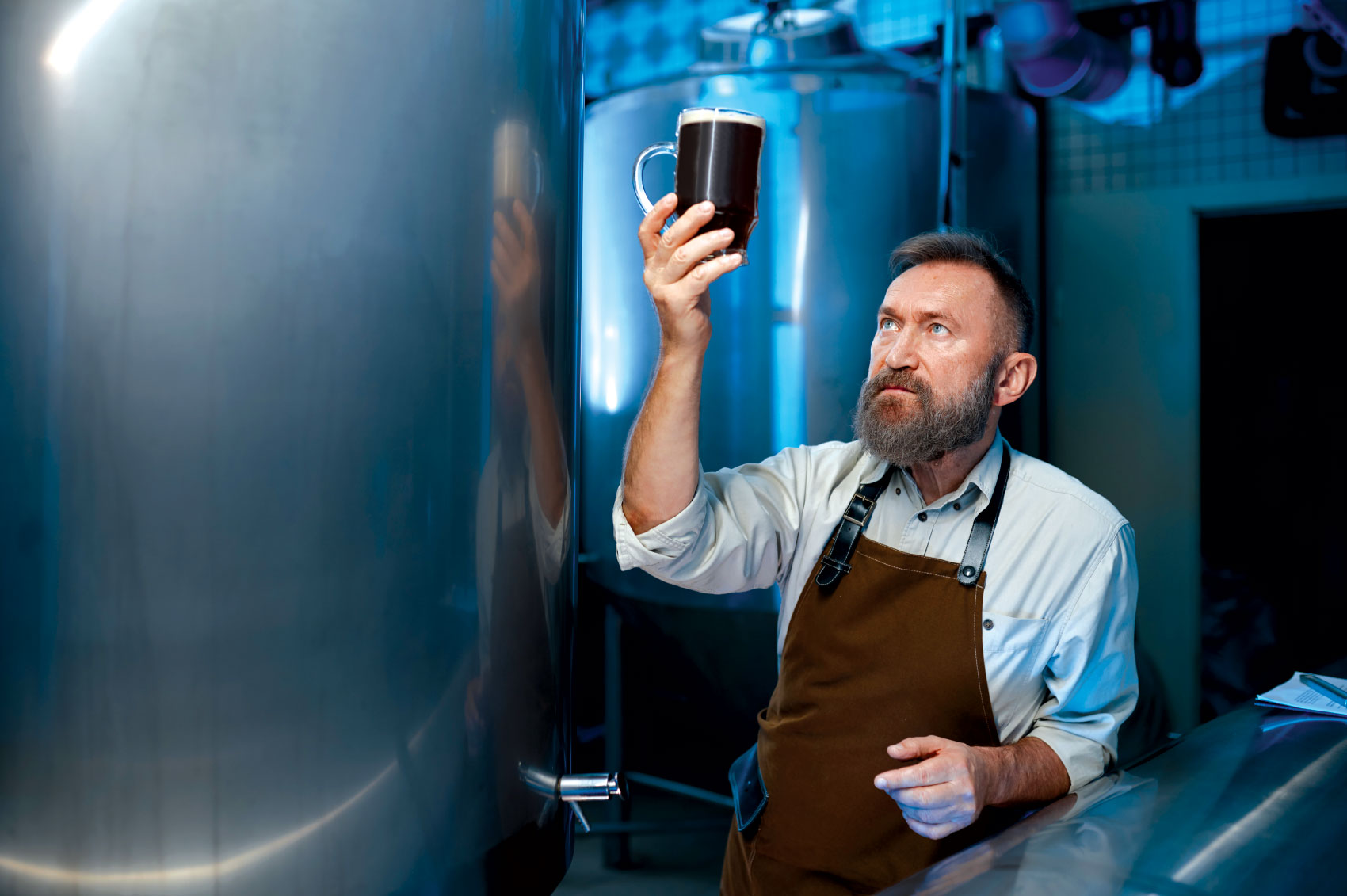 Brewer taking close look at beer in raised glass