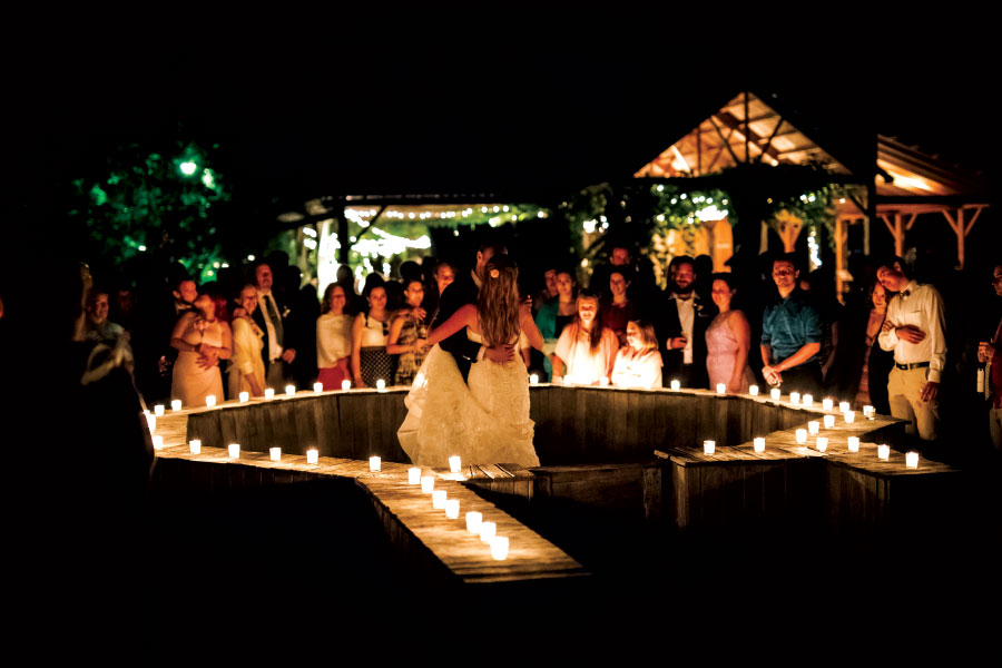 Woman in white dress surrounded by candles and group of onlookers