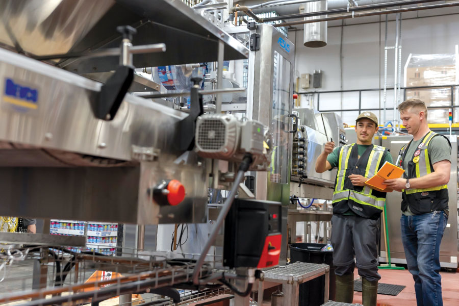 Two men in safety vests inspecting brewing equipment