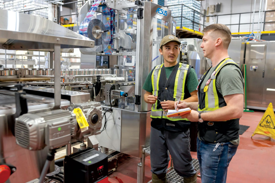 Two men in safety vests chatting in brewery