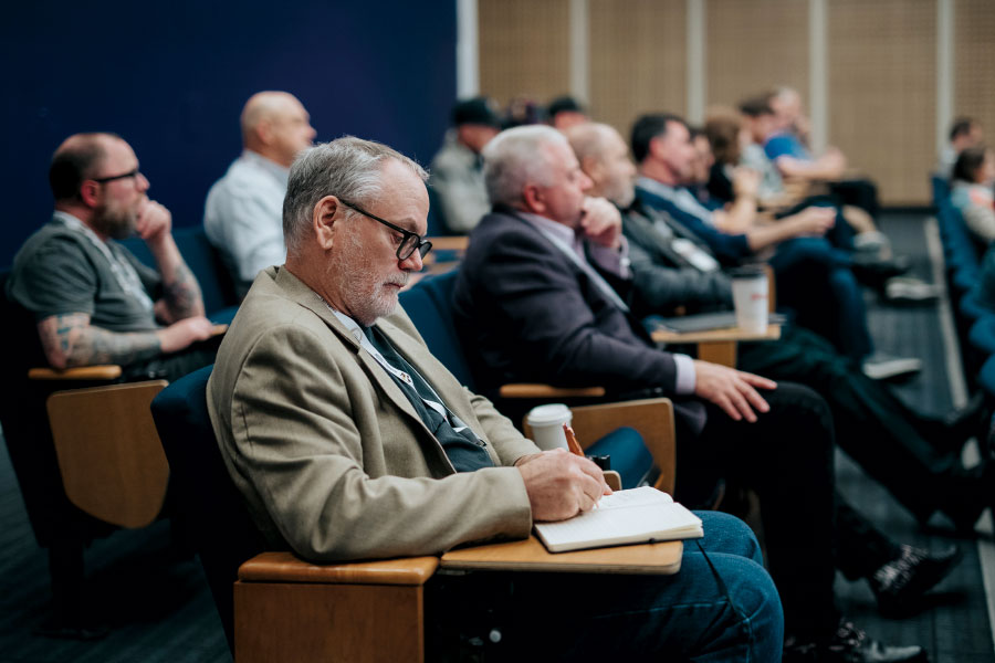 Man in audience jotting notes