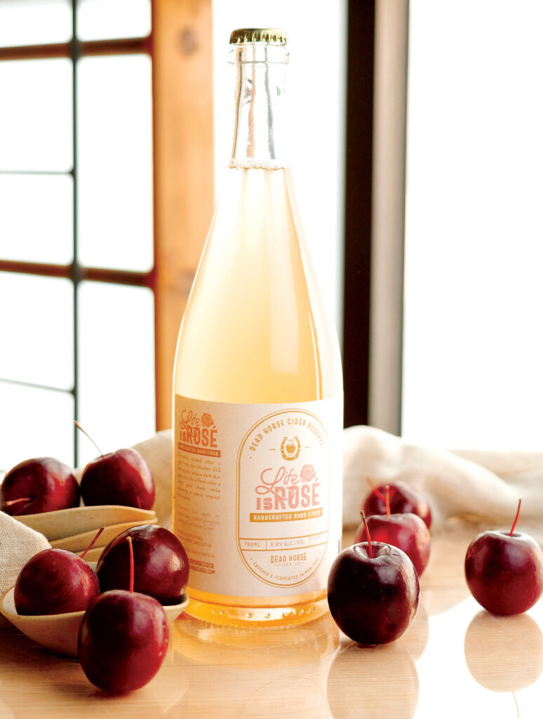 Bottle of Life Is Rosé hard cider and red apples on table