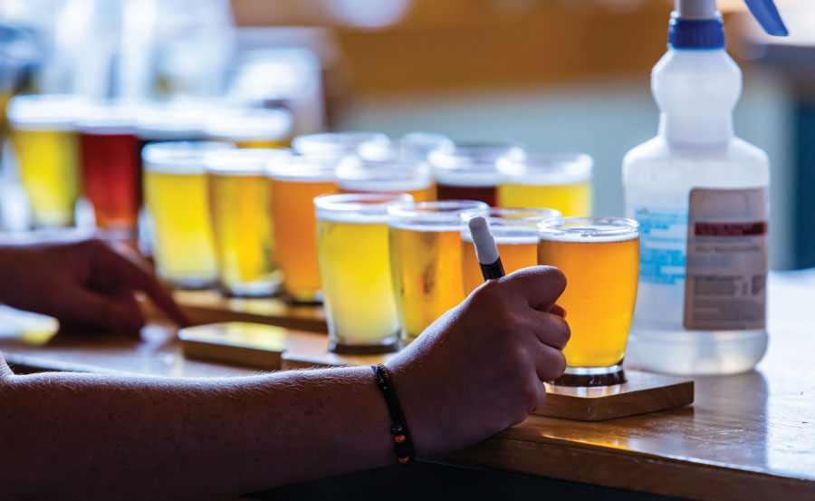 Making notes with flights of beer on bartop in background