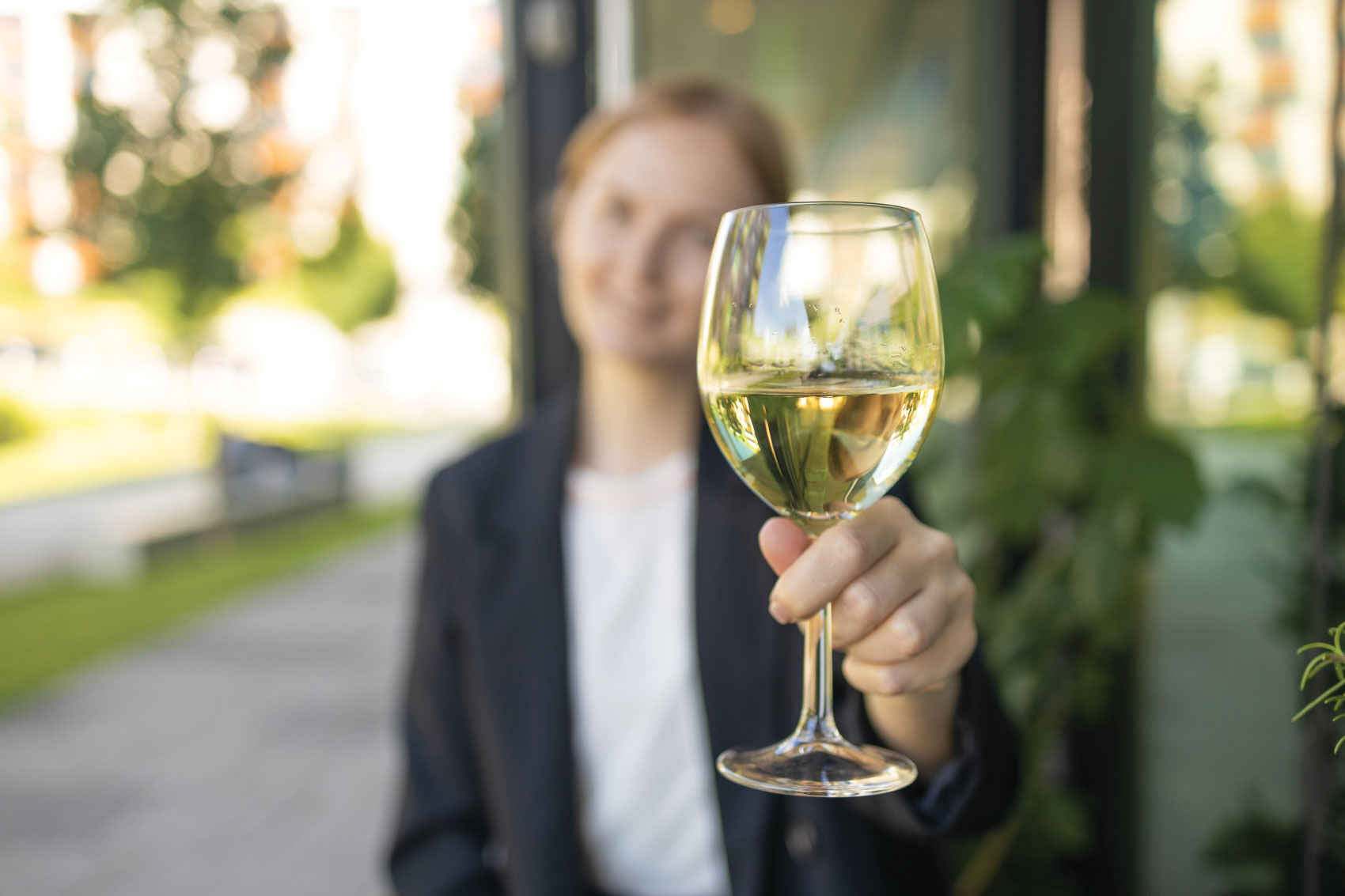 Woman holding a glass of white wine up to the camera