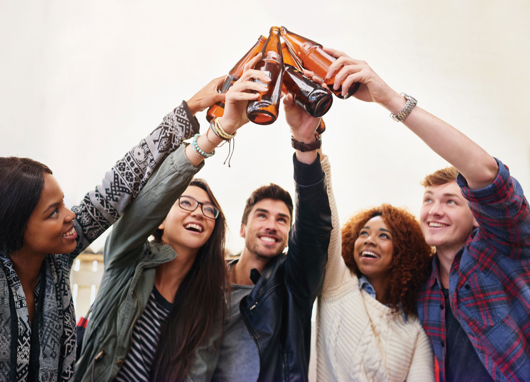 Group of young adults toasting with beverages in hand