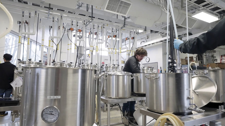 Student in lab full of various stills and brewing equipment