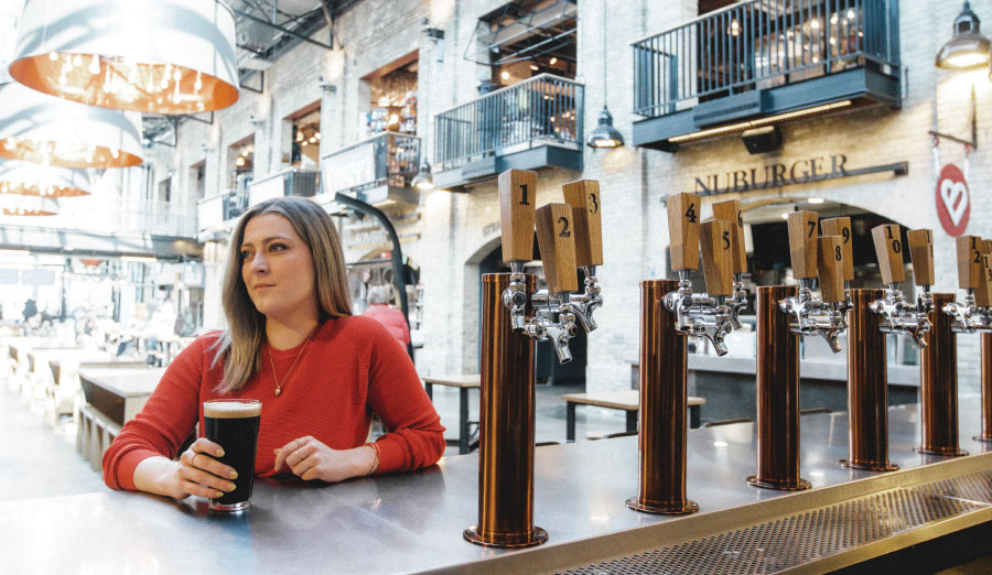 Lauren Richard sitting at bartop with pint of dark beer