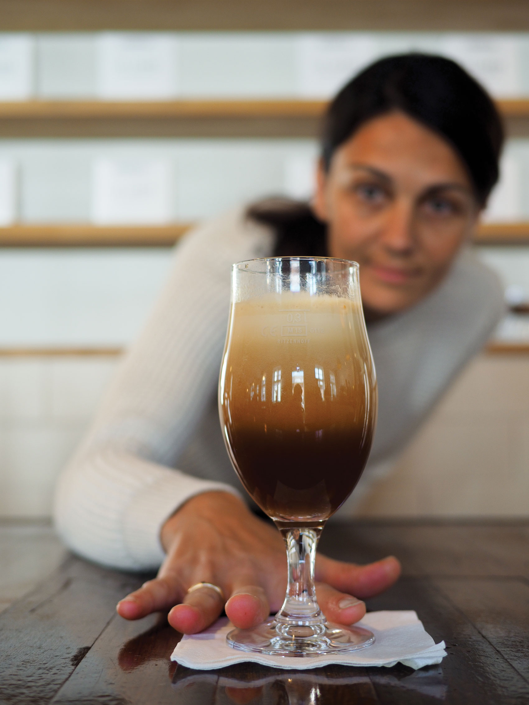 Woman sliding glass of beer towards camera