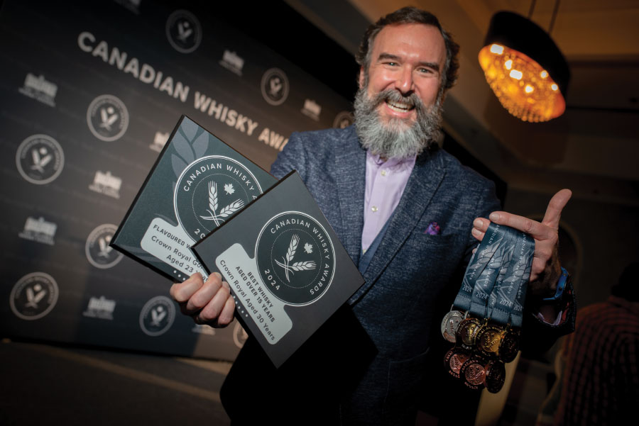 Stephen Wilson smiling with two handfuls of awards